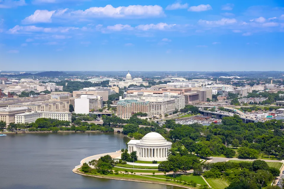 Luftbild des Tidal Basin mit dem Jefferson Memorial am Ufer, dahinter Bürogebäude und in der Ferne das Kapitol.